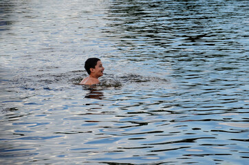 A happy boy is swimming in the lake. A happy child bathes in the sea. Laughing young boy in the...