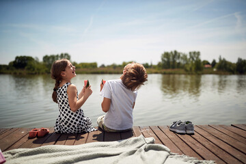 cute minor brother and sister laughing at riverside,  sitting by the river eating watermelon