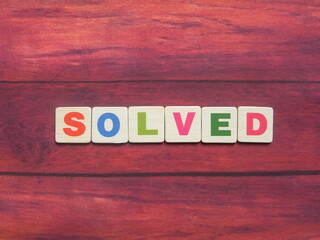 Word Solved on wood background