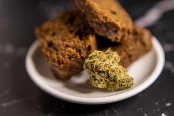 Close up of cannabis infused brownies with a cannabis bud on a white plate
