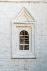 Russia, Uglich, July 2020. The original narrow window on the white wall of the old church.