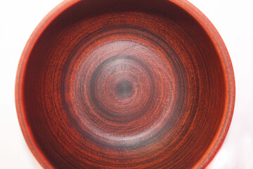 Empty earthenware deep plate on a white background, top view, close-up. A brown plate with small black stripes around the circumference. Dishes.