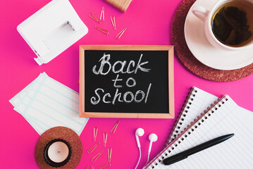 Back to school flat lay: chalk board, candle, cup of tea and various school stationery items on pink background. Secondary education