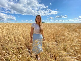 beautiful woman walks in a field with ears, takes pictures in a wheat field
