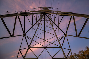 Steel lattice tower for the transmission of electrical energy with blue sky and pink clouds in the background