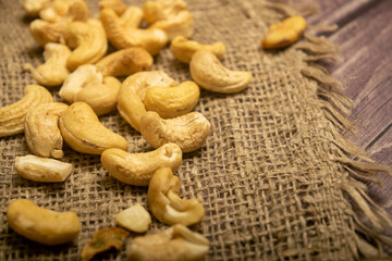 A pile of cashew nuts on burlap with a rough texture surface texture. Close up.