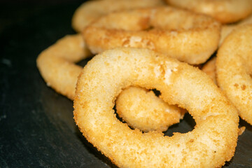 Homemade onion rings on a black table. Close up.