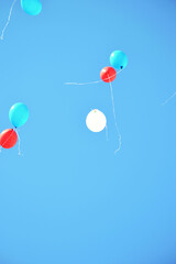 Fototapeta na wymiar Red, blue and white balloons flying high in the sunny blue sky as festive background. Happy Birthday. Back to school