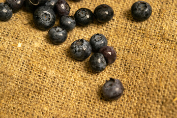 Blueberries scattered on a background of homespun fabric with a rough texture. Close up.