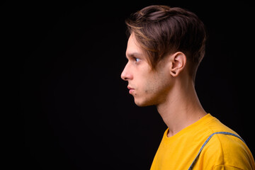 Young handsome rebellious man against black background