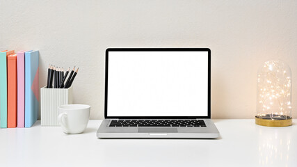 Fototapeta premium Stylish workspace with laptop, lightbulb, coffee cup, office equipment and blank screen laptop on white table in home office. Front view. concept work from home.