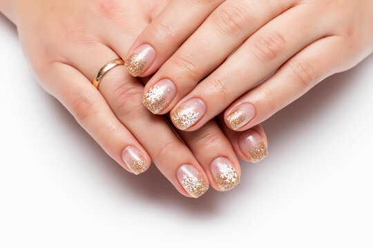 Winter manicure with painted snowflakes. Golden shiny manicure on square short nails close-up on a white background
