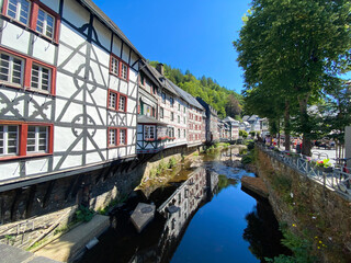 Fototapeta na wymiar Monschau, Germany (Eifel) - July 9. 2020: View on river with timber frame monument houses in center of medieval village (focus on left house)