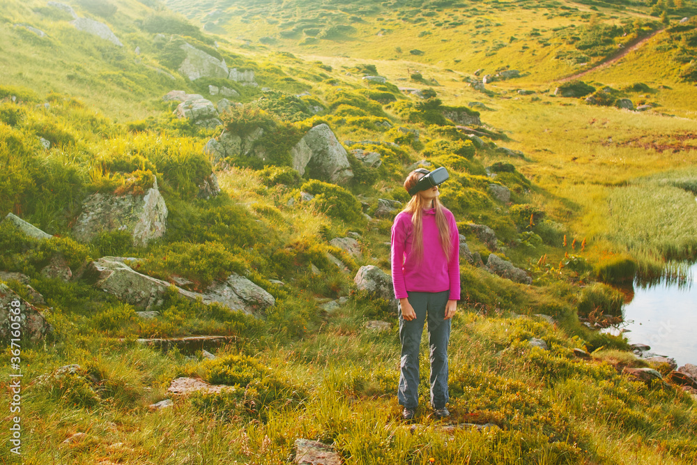 Wall mural woman in virtual reality glasses standing near a mountain lake