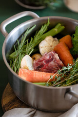 Ingredients for cooking bone broth close-up. Stock pot with veggies, herbs, and beef. Vertical orientation