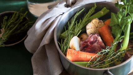 Ingredients for cooking bone broth. Stock pot with veggies, herbs, and beef. Horizontal orientation