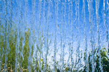 The texture of a transparent water wall from jets of water flows down. Close-up view