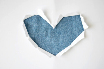 Jeans textile hole with torn sides in shape of heart on white background for copy space. Template for advertising, print or promotional content.