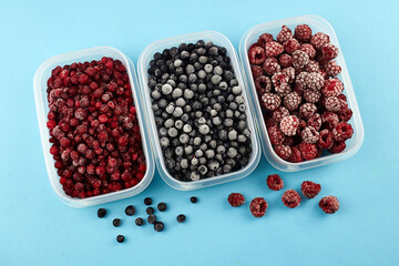 Frozen berries: blueberries, cranberries and raspberries on a blue background