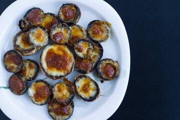 Baked with butter and cheddar mushrooms in plate on the dark surface