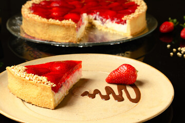  slice of strawberry pie with ground cashew nuts on a dark glass table
