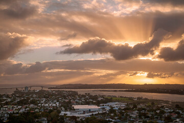 Sunbeams shine through dramatic clouds at sunset in New Zealand.