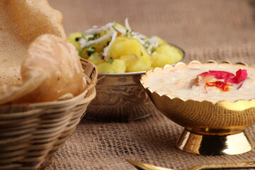 Puri/Bhaji and kheer - Indian semi dry Potato Spicy recipe also known as Batata or Aloo ki Sabji, served with fried Poori and khir
