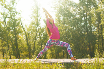 Young caucasian brunette woman doing yoga in summer forest.