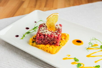 Beef tartare with mango, garnished with sesame seeds and a slice of dehydrated orange