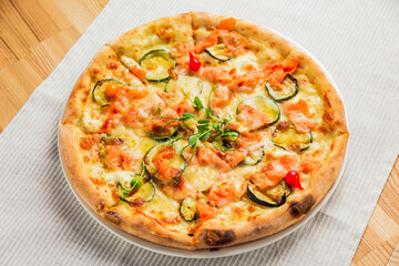 Pizza with zucchini, red fish and cheese, on a white plate