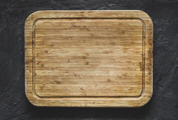 Top view of wooden chopping board on grunge grey background. Copy space design. Mockup for food concept.