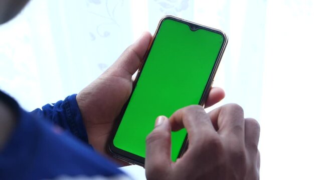 back view of man holding smart phone with green screen 