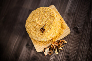 homemade honey cake decorated with golden wooden flowers on dark background