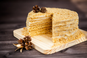 homemade honey cake decorated with golden wooden flowers on dark background
