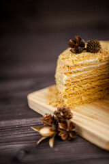 homemade honey cake decorated with golden wooden flowers on dark background