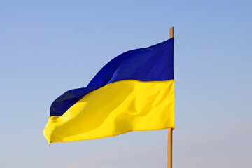 Yellow-blue flag of Ukraine and blue sky as a background. Flag is waving  on the wind