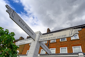 A local sign with pointing hands in Dulwich Village, Greater London, UK. The sign shows directions...