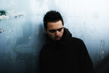 Close-up of a young brunette male alcoholic in an underpass.