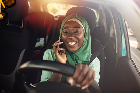 Portrait of a Middle Eastern woman driving a car and talking on smart phone  she is wearing a modern Abaya. Emirati woman driving a car. Arab Women Driving