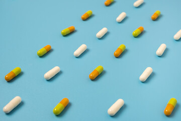 Close up of many different pills arranged in pattern on blue background.