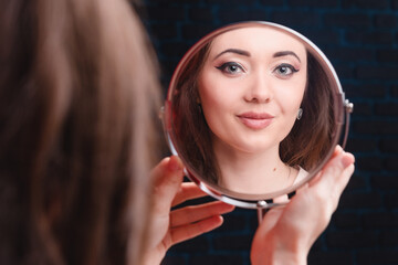 Attractive young girl looks in the mirror, close-up. The concept of youth, beauty and personal care