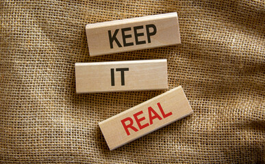 Wooden blocks form the text 'keep it real' on beautiful canvas background. Business concept.