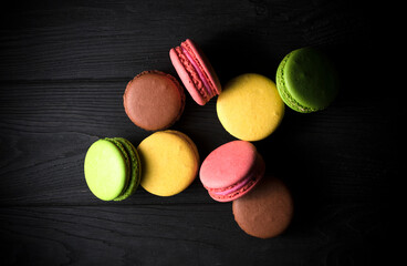 colored macaroons on a black wooden background