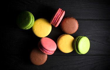 colored macaroons on a black wooden background