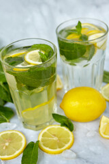 Refreshing drinks for summer, cold sweet and sour lemonade juice in the glasses with sliced fresh lemons. Refreshing summer drink. Traditional lemonade with lemon, mint and ice. Selective focus