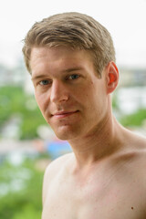 Young handsome shirtless man against view of the city with nature