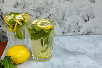 Refreshing drinks for summer, cold sweet and sour lemonade juice in the glasses with sliced fresh lemons. Refreshing summer drink. Traditional lemonade with lemon, mint and ice. Selective focus