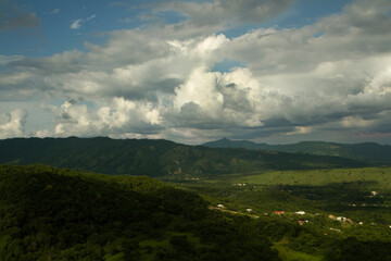 Countryside landscape. Aerial view of the village in the green valley at the foot of the hills, under a dramatic sky, 