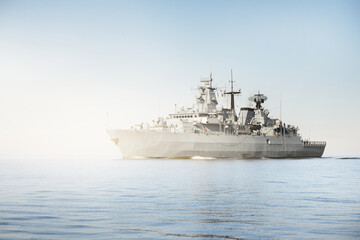 Large grey modern warship sailing in still water. Clear blue sky. Baltic sea, Germany. Global...
