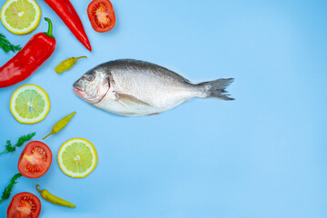 Dorado fish and vegetables: cucumber, tomato, pepper, lemon lie on a blue background. Background texture for the kitchen